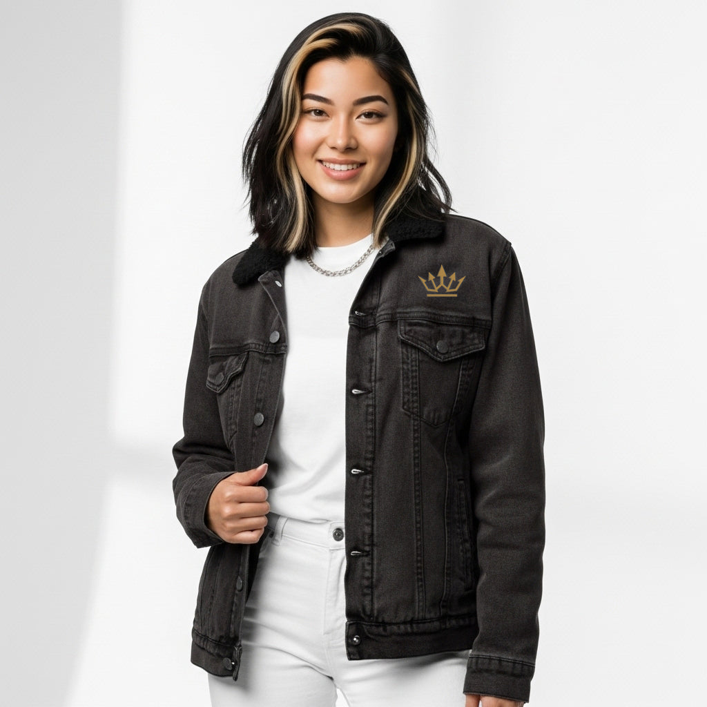 Person wearing a black denim jacket with a gold crown emblem on a white background