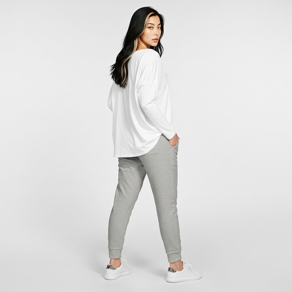 Woman wearing a white oversized shirt and gray sweatpants on a white background