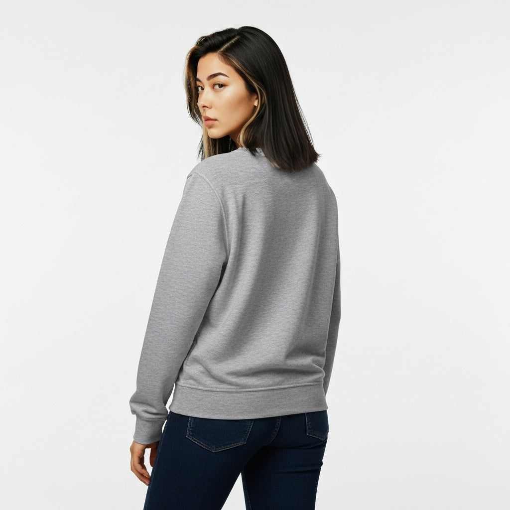 Person wearing a gray sweater and dark jeans on a light gray background